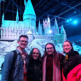society members posing in front of hogwarts castle model
